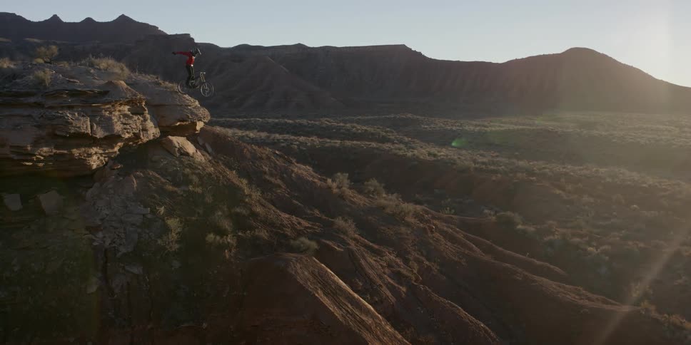 A person jumps off a mountain on a bicycle