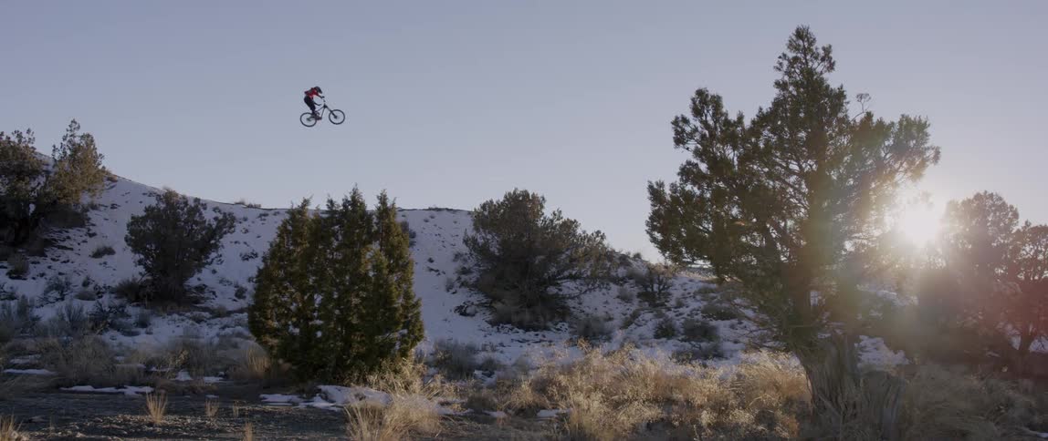 A bicyclist flies through the air in a rural area