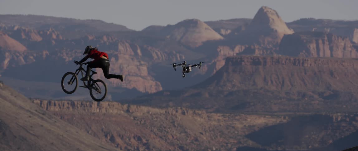 A person doing bike tricks followed by a drone