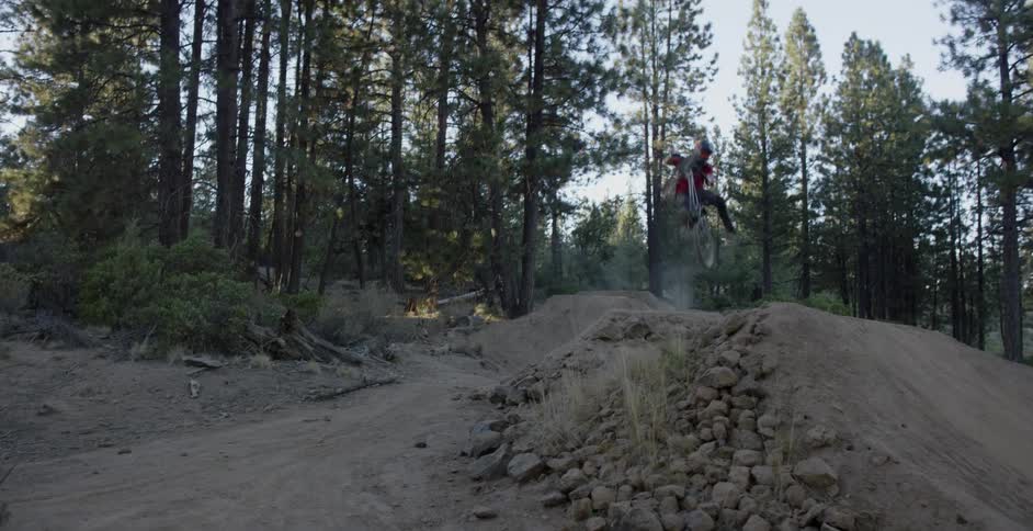 A person rides their mountain bike jumping over hills