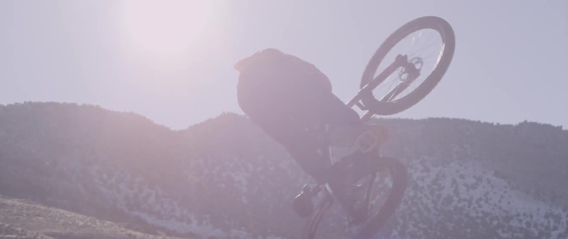 Person jumps a bike over a small hill in the desert