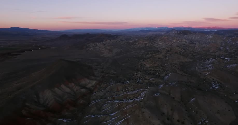Snow and ice sparsely cover the hilly landscape