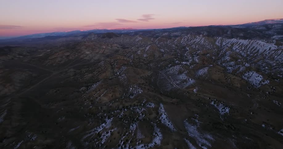 Snow covers areas of ridges and peaks at sunset