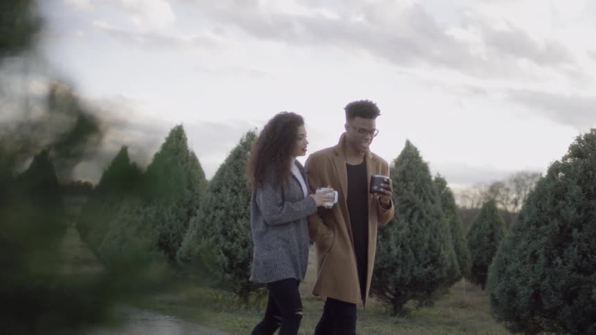 Man and woman drink hot chocolate on a tree farm