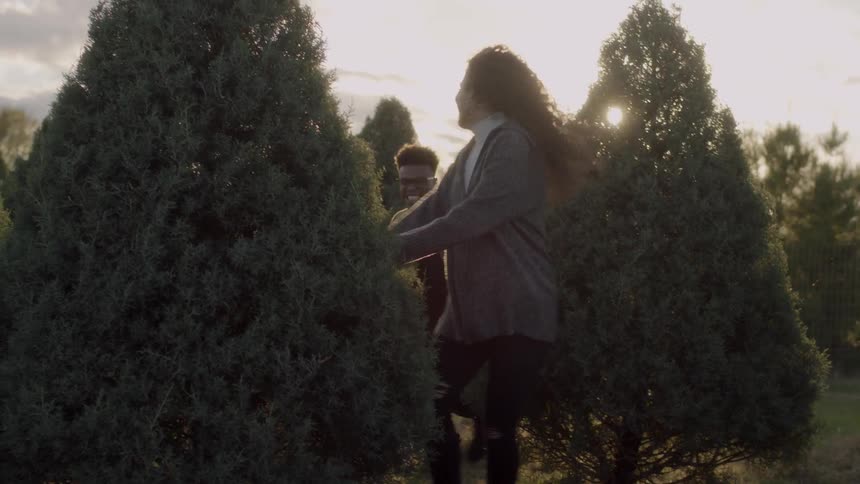 Man and woman run on a tree farm