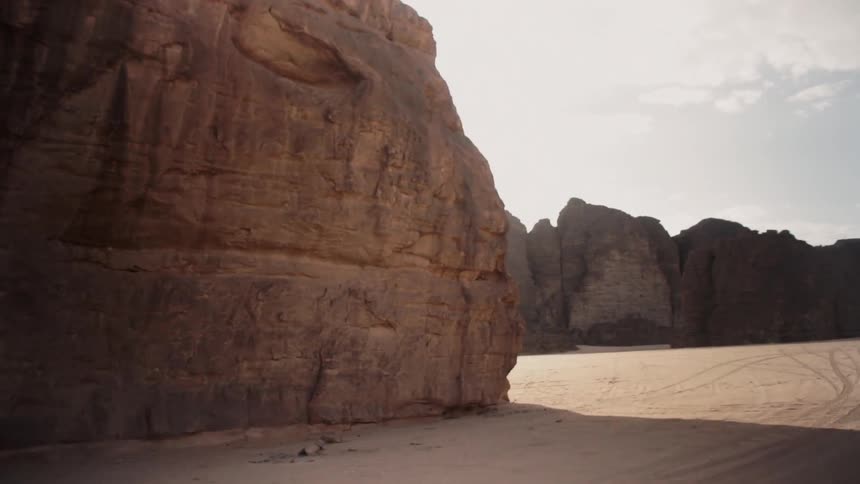 The sun is casting shadows on rock formations in a desert landscape