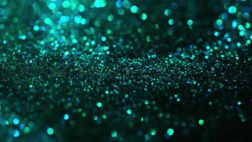 Green and blue granules are poured and gather together in a pile