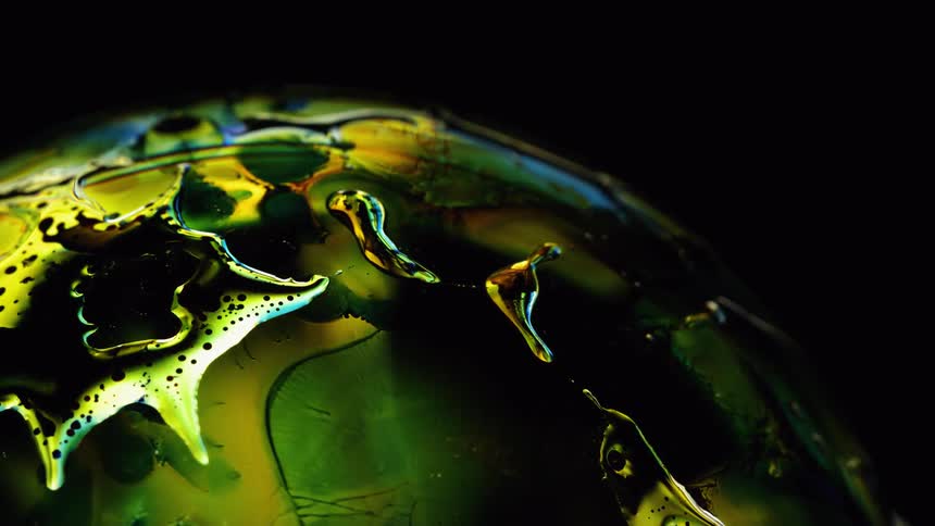 Colorful liquids flowing over a lighted globe against a dark background