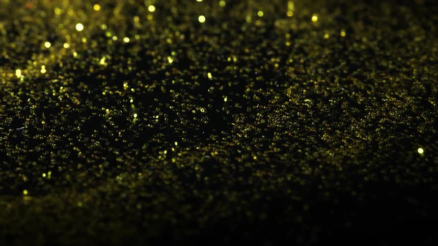Gold and yellow glitter vibrates on a black surface