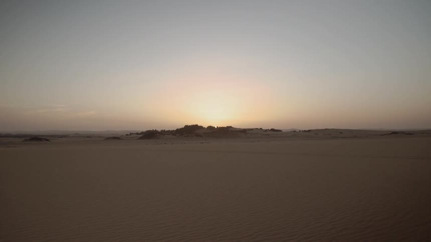 The sun is rising over a desert landscape