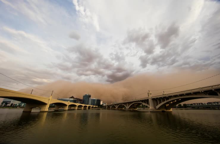 A sandstorm blows across bridges in an urban setting during the day