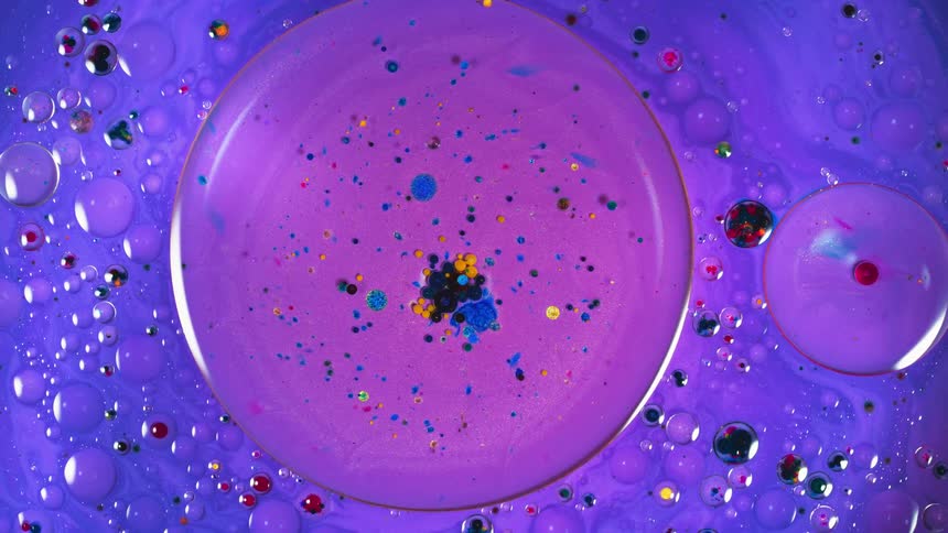Purple liquid with multi-colored specks turn in a circle