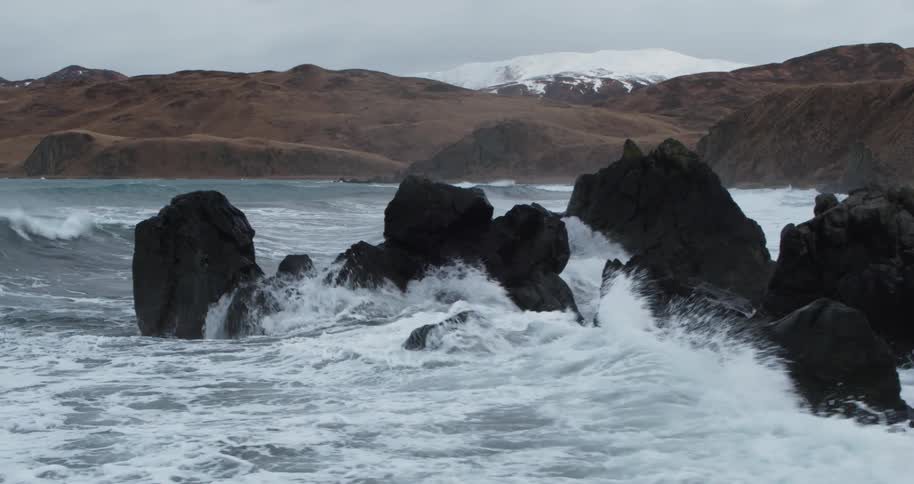 Waves are crashing against rocks on a winter's day
