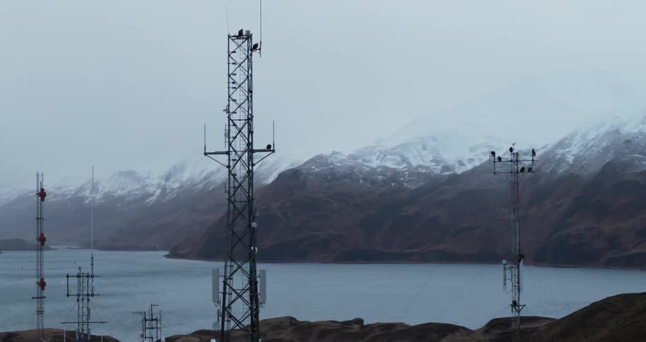 Metal tower near a body of water and eagles and mountains