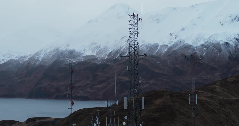 Communications towers are standing on a hilltop in a mountain range in winter