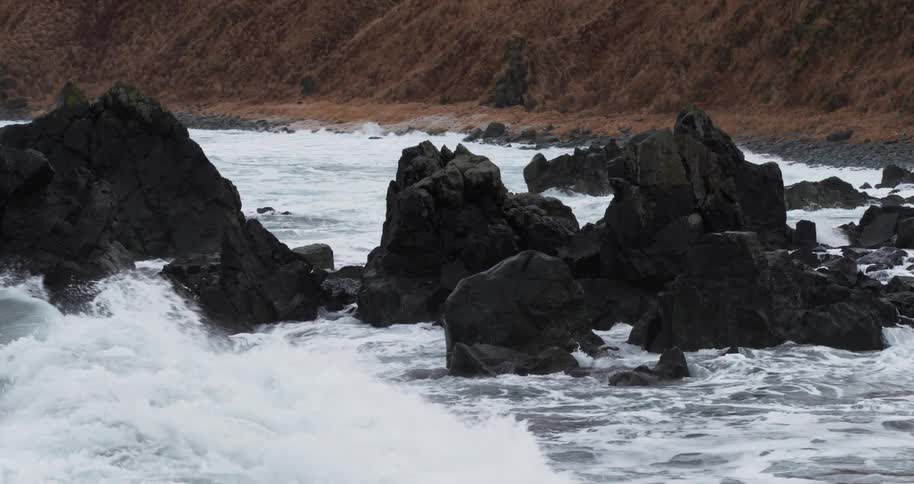 Waves crash into rock formations by the shore