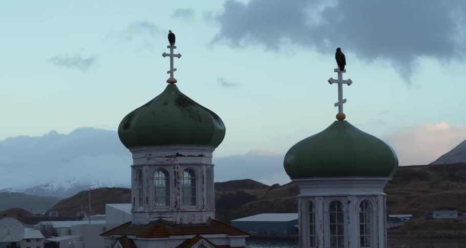 Eagles are perching on crosses atop a church at dusk