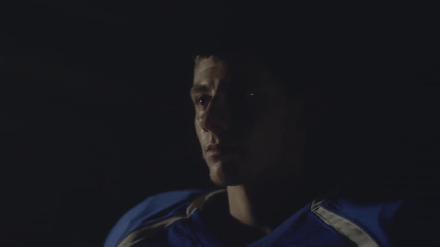 A young man in an athletic uniform stares into the distance