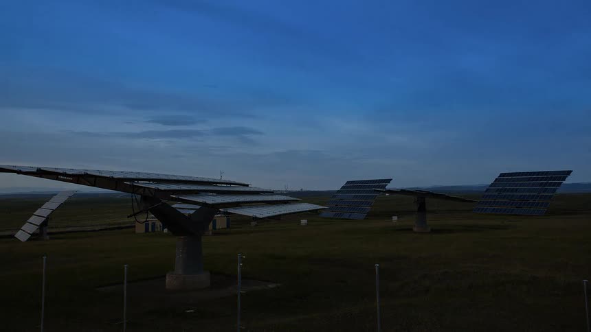 Solar panels rotate in a rural field at sunset