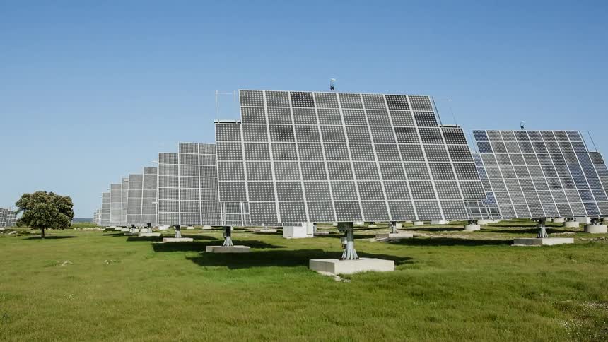 Solar panels rotate in a grassy field
