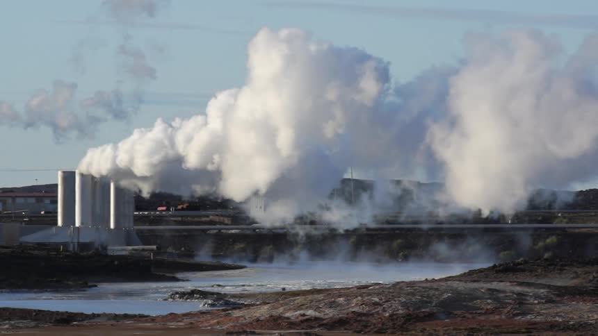 Steam billows from industrial smoke stacks on a cold day