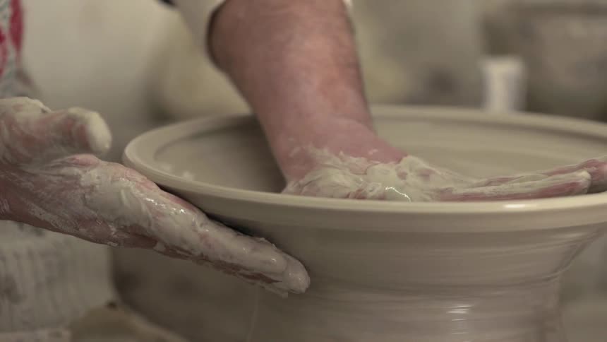 A man shapes pottery on a pottery wheel