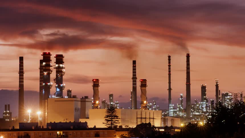 Smoke stacks puffing out pollution at sunset