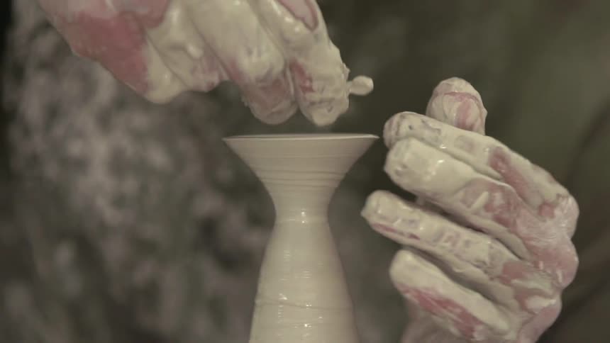 A man shapes pottery on a pottery wheel
