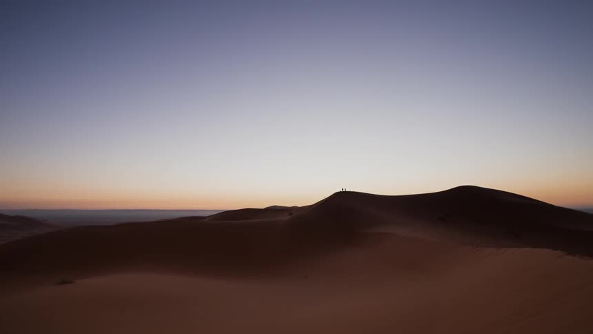 The sun rises over sand dunes