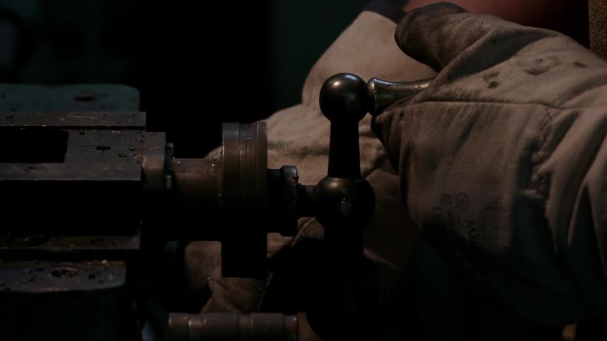 A man uses machinery while wearing an apron and gloves