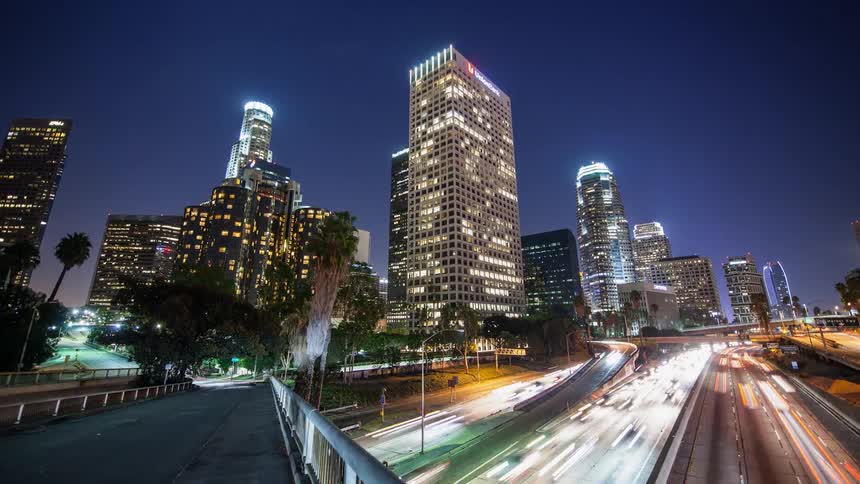 Traffic is flowing on a freeway in an urban area at night