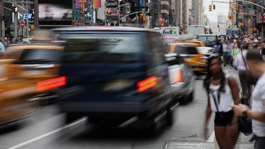 Cars and pedestrians travel on a city street