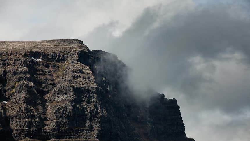 Clouds are rushing across cliffs during the day