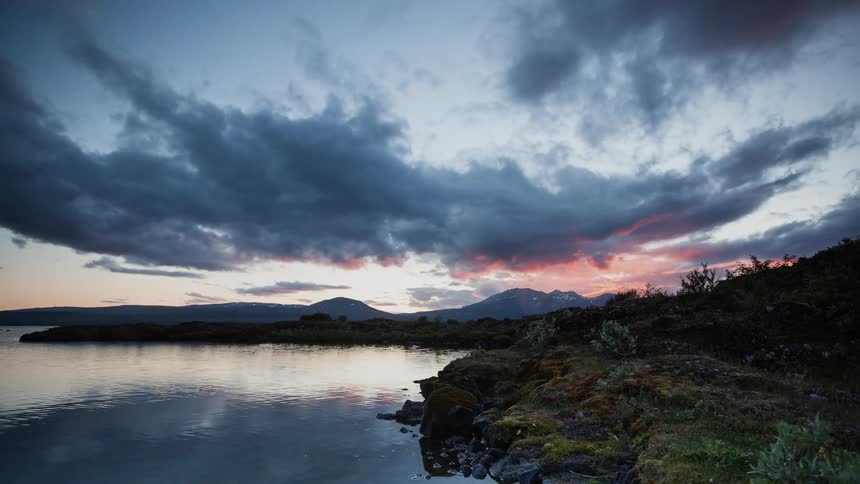 Clouds float over a mountain lake at sunset