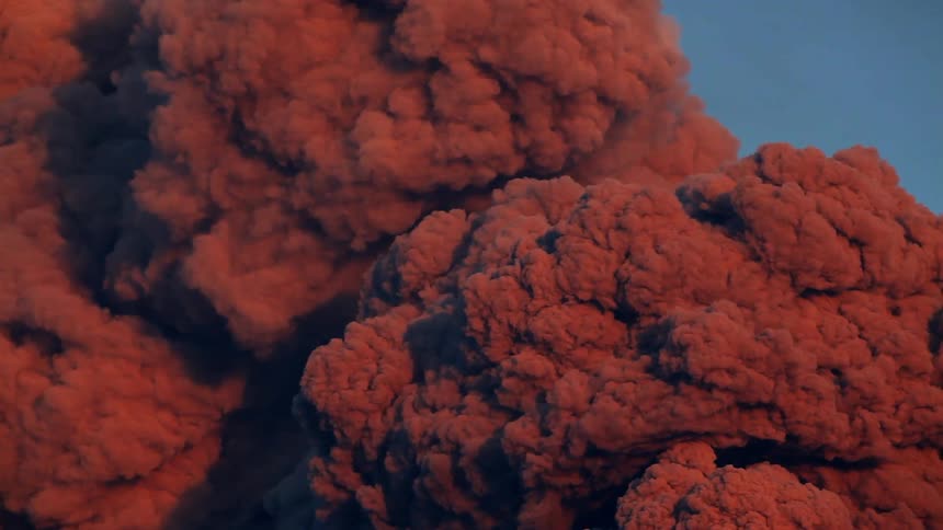 Red smoke from a volcano expands and rises