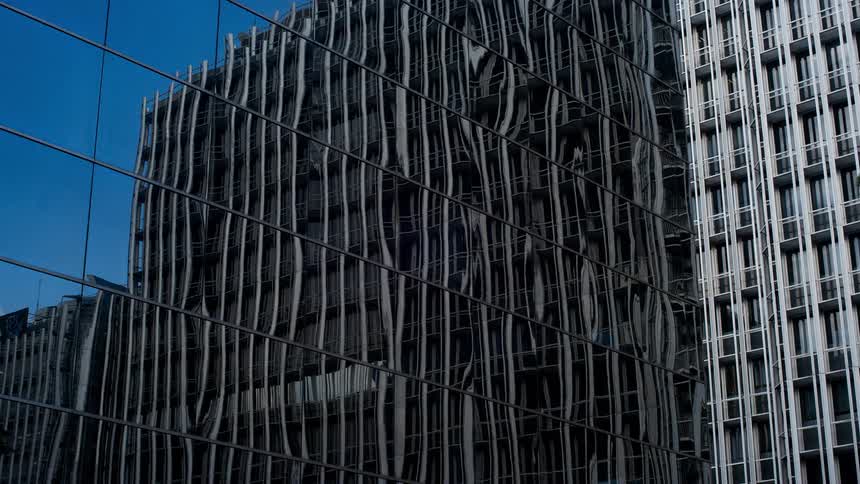 The sky is reflected on an all glass exterior of a building