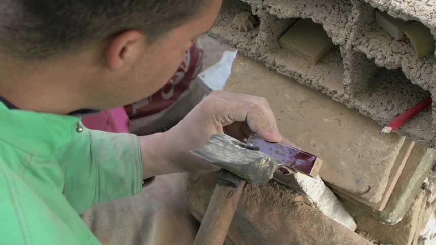 A man breaks off pieces of tile using a hand tool
