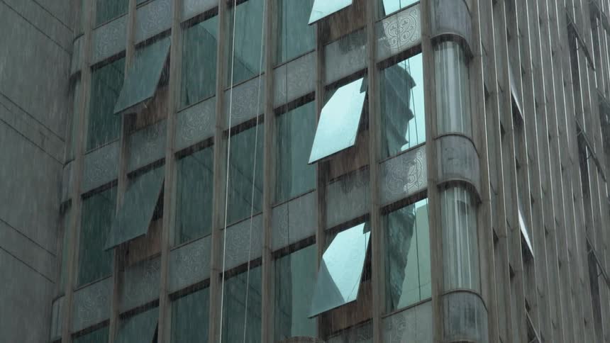 Rain falling before a tall building in a large city