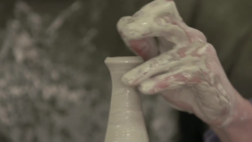 Person molds a vase out of a clay on a pottery wheel