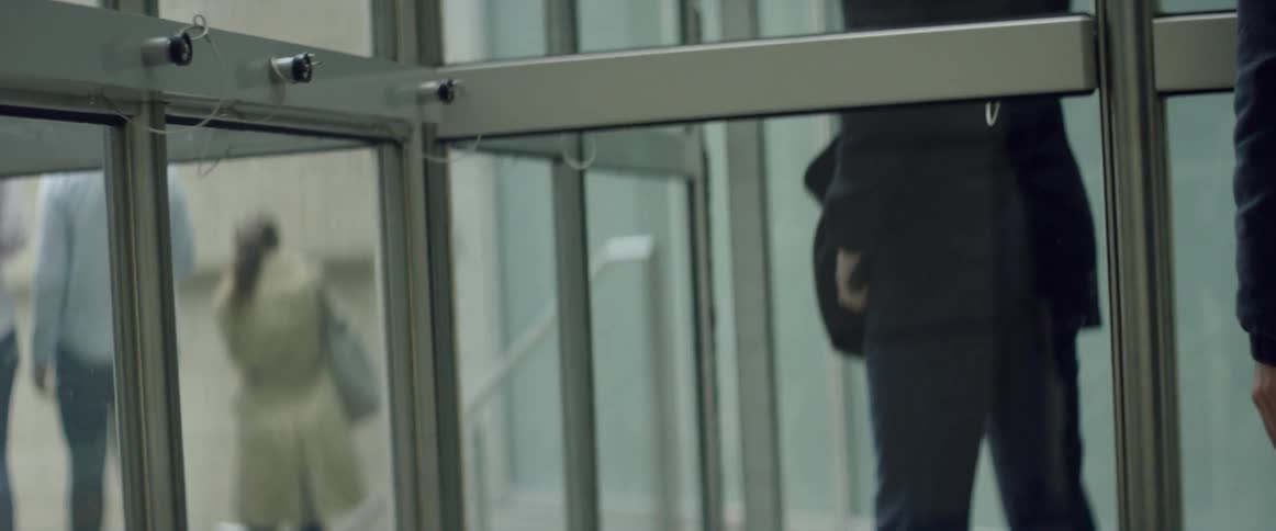 People are walking out of a revolving door in a building during the day