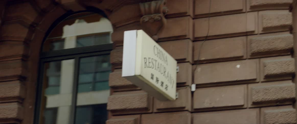 Passing view of a sign indicating a china restaurant attached to a block wall in a city
