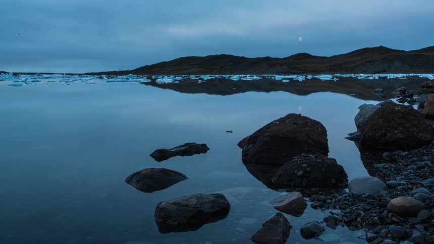 Timelapse of a calm river next to a rocky shore