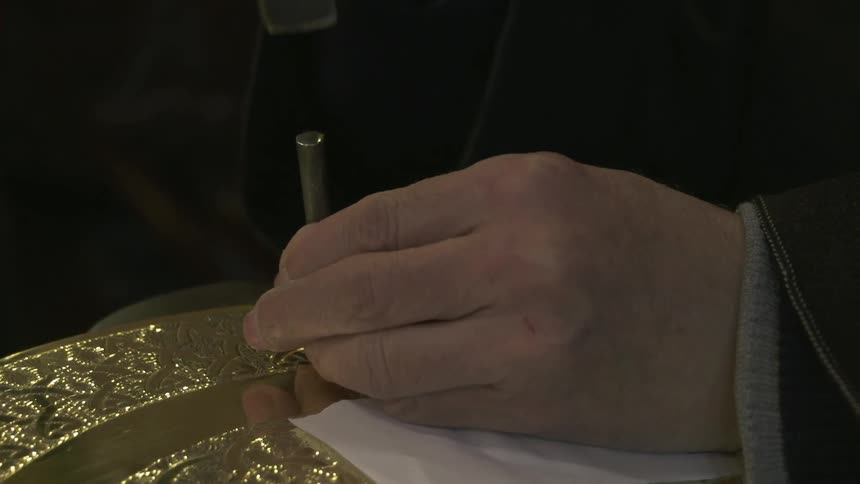 A craftsman uses a chisel and hammer to create a design