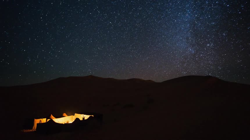 Tents glow beneath a starry night sky