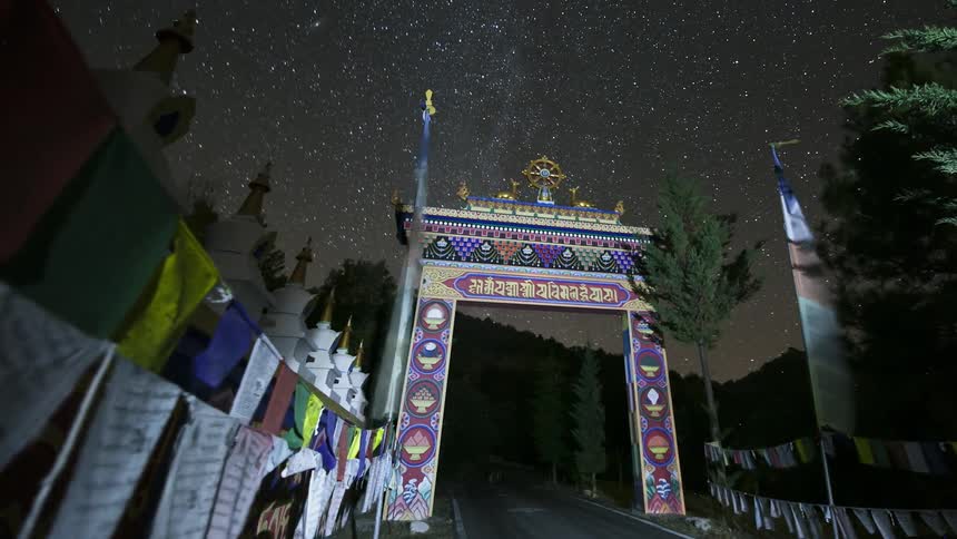 Flags leading to an asian gate blow in the wind as stars pass overhead