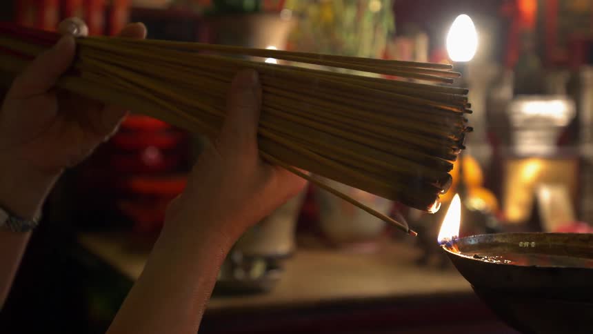 A woman lights a bundle of incense