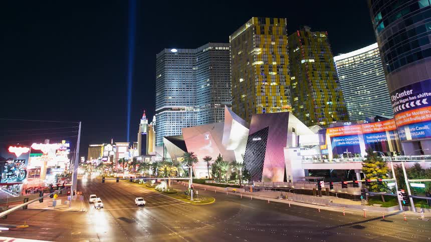 Traffic is flowing through a city intersection at night