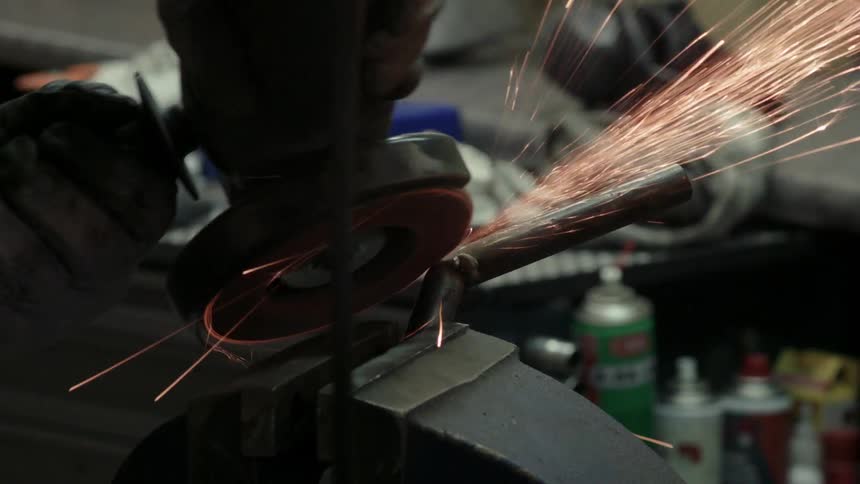 A person is using a grinder to sand the weld on a pipe
