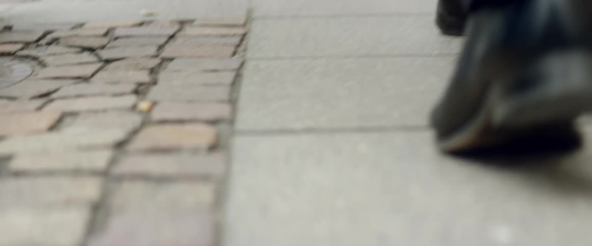 People's feet as they walk on a sidewalk in a city