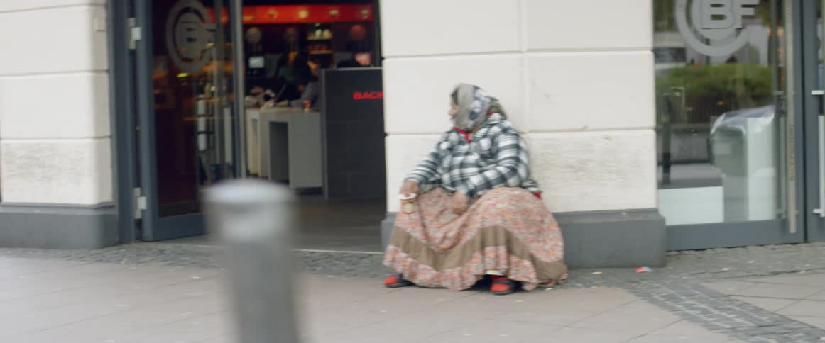 Woman sits outside of a building on a busy city street